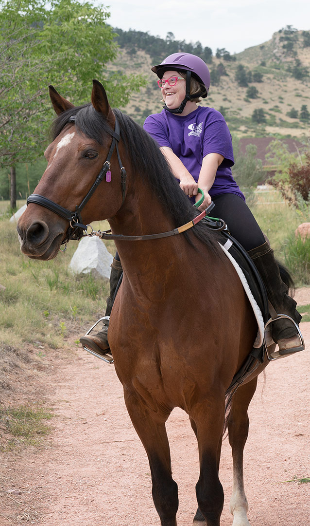 A happy participant with downs syndrome at Hearts & Horses in Loveland, Colorado
